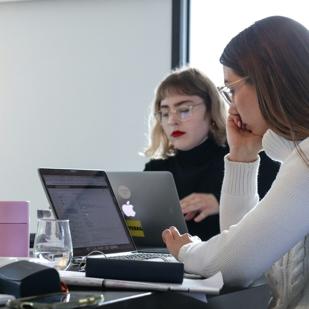 Team of people collaborating around a table with laptops